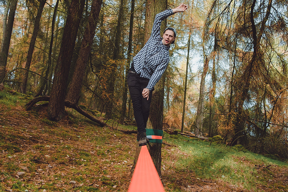 man walking on slackline in forest (6650769768521)